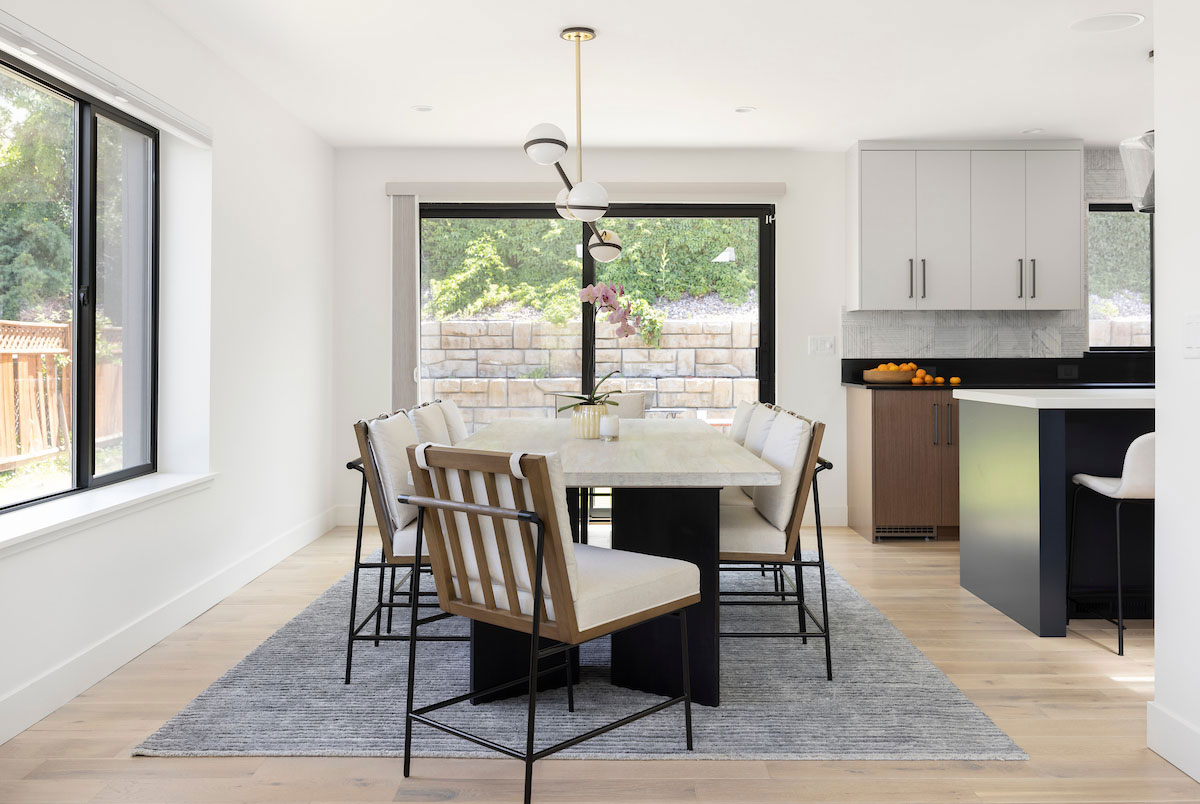 Dining area in kitchen with large windows.